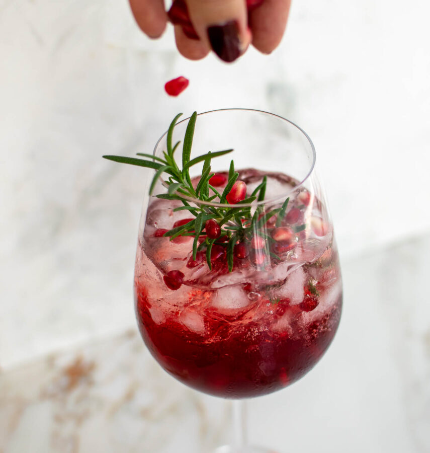 Pomegranate Campari Spritz with pomegranate arils being sprinkled in.