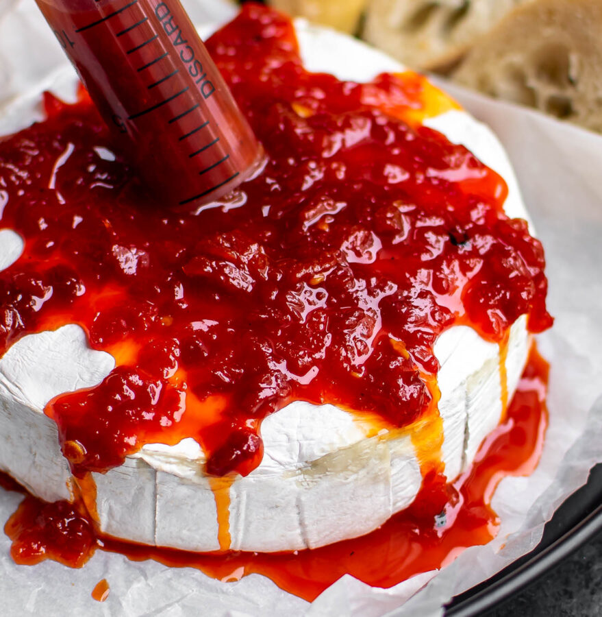 Baked brie with pepper jelly "blood" in a syringe.