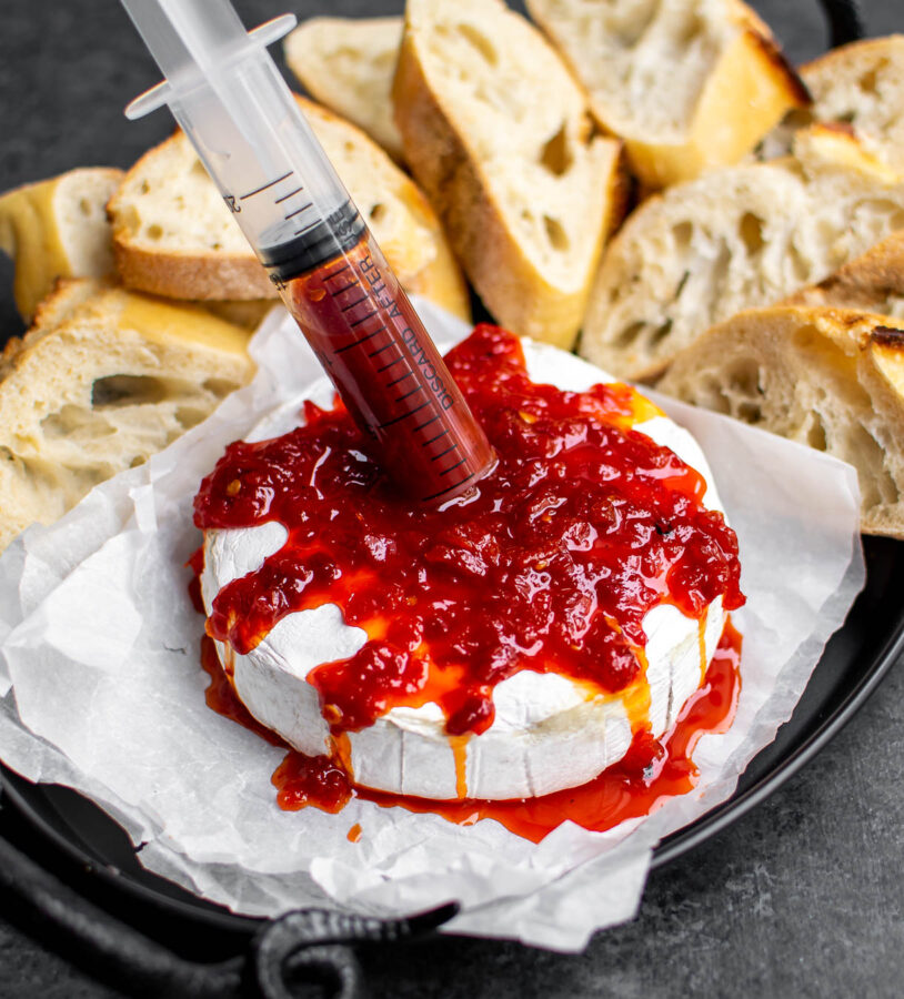 Baked Brie with pepper jelly "blood" in a syringe.